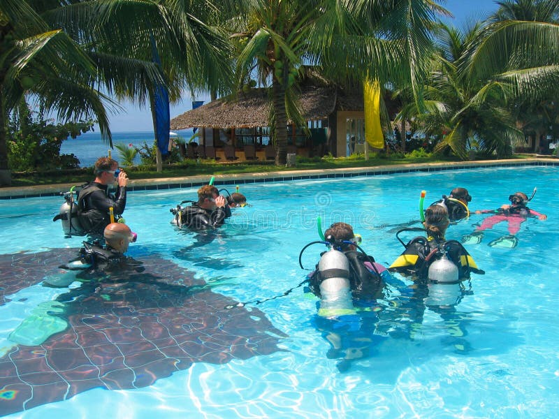 A group of scuba divers learning how to dive in a class held in a tropical swimming pool. A group of scuba divers learning how to dive in a class held in a tropical swimming pool