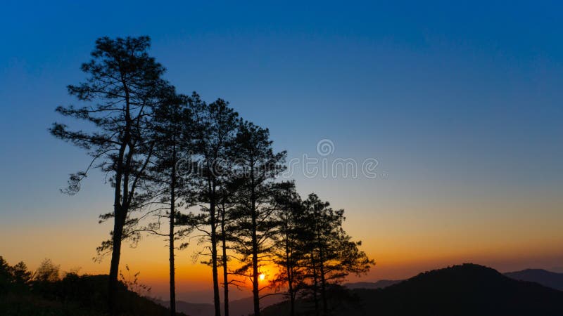 冬山的美丽日落. 夕阳照耀着一片安详的山景，覆盖着热带树木 库存图片