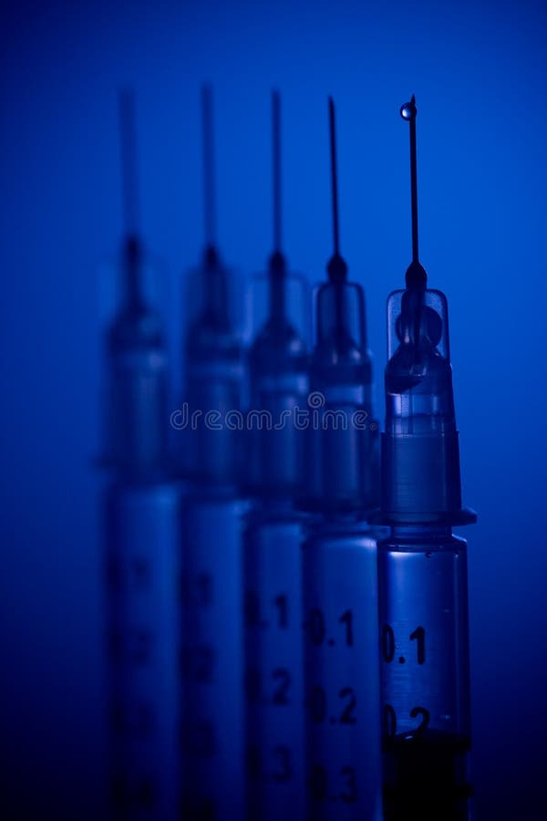 A row of uncapped needles lined up for injecting medicine. A row of uncapped needles lined up for injecting medicine.