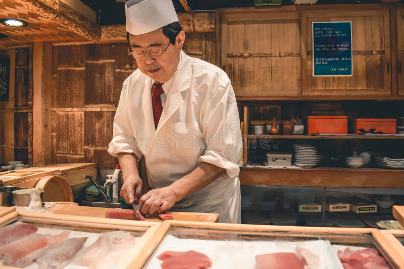 准备新鲜的金枪鱼生鱼片早餐的寿司大厨在Tsukiji鱼市上在东京