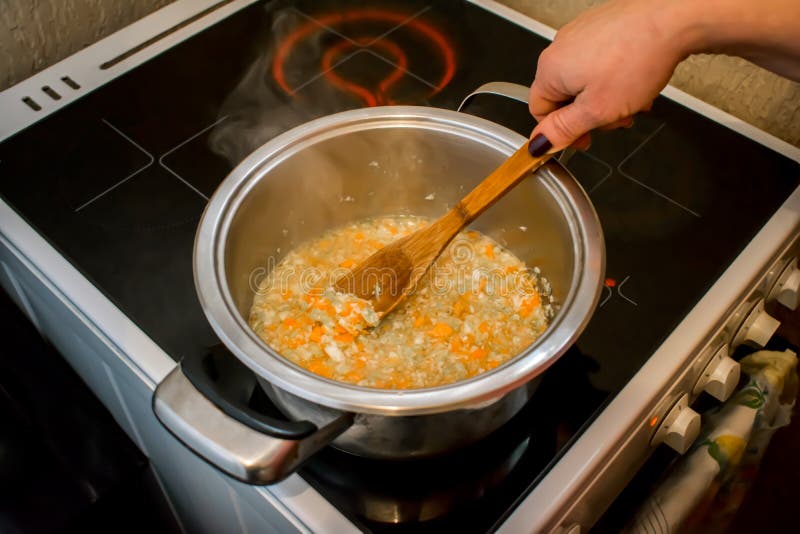 Chopped soup ingredients: carrots, onions and celery cooking in a stainless steel pot. Chopped soup ingredients: carrots, onions and celery cooking in a stainless steel pot.