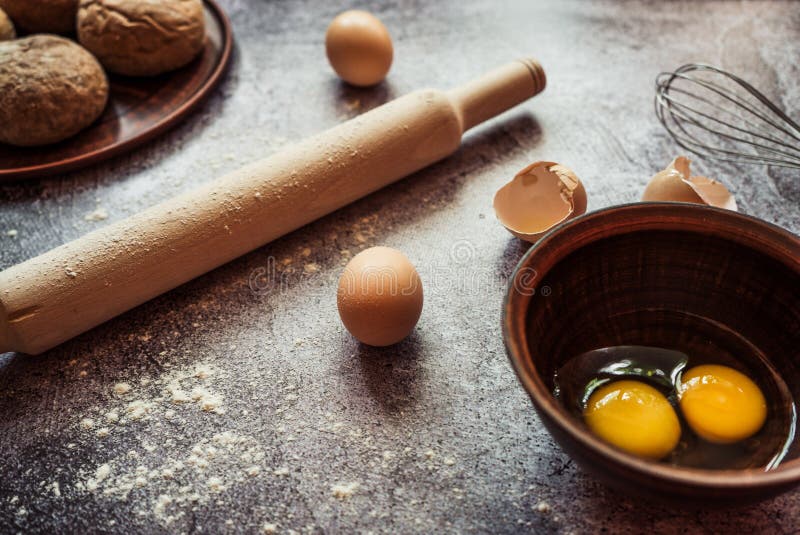 Ingredients for baking bread, eggs, rolling pin, mixer lie on a gray table. Ingredients for baking bread, eggs, rolling pin, mixer lie on a gray table