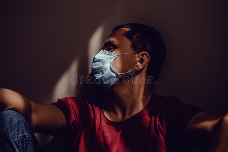 医用面罩坐斜墙中光影图案伤心成年男子侧视轮廓肖像 保持隔离 免版税库存照片