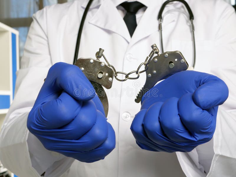 Medical negligence or neglect concept. Doctor stands in handcuffs. Medical negligence or neglect concept. Doctor stands in handcuffs