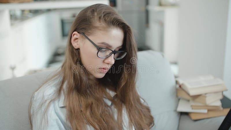 十几岁的女孩在膝上型计算机在笔记本读了文本，看屏幕，写某事，为检查做准备