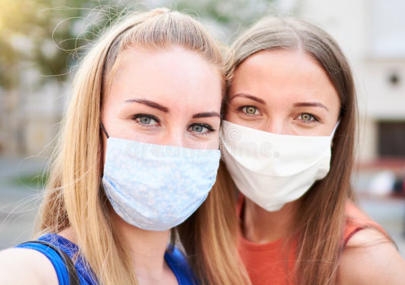 千禧一代的女性朋友戴着口罩笑着自拍 - 新常态夏季友谊概念，年轻女孩们玩得很开心 库存图片