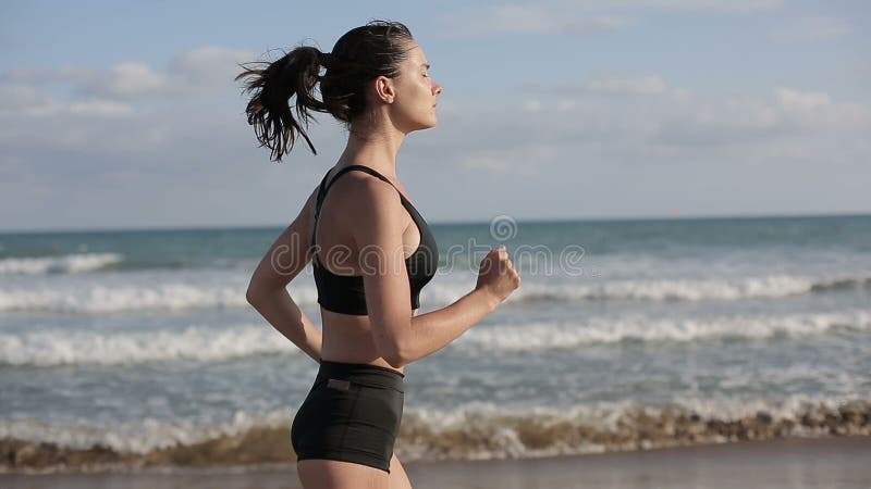 单独跑在海滩的美好的日落的妇女