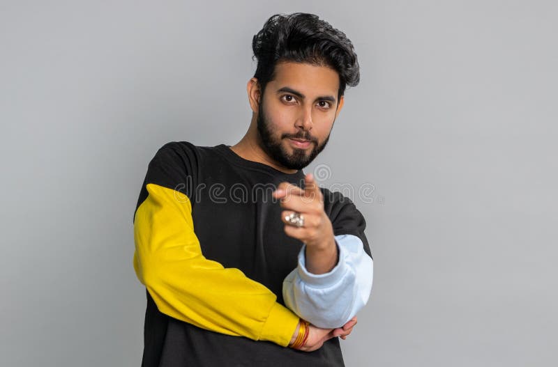 Hey you. Young indian man smiling excitedly and pointing to camera, choosing lucky happy winner, indicating to awesome you. Handsome bearded hindu guy isolated alone on gray studio wall background. Hey you. Young indian man smiling excitedly and pointing to camera, choosing lucky happy winner, indicating to awesome you. Handsome bearded hindu guy isolated alone on gray studio wall background