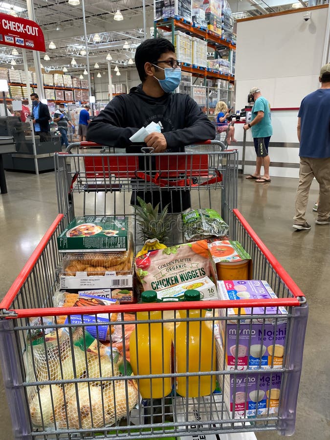 Frisco, TX / USA - September 2, 2020: Indian man wearing a mask holding his shopping cart with grocery in the Costco check out area. Frisco, TX / USA - September 2, 2020: Indian man wearing a mask holding his shopping cart with grocery in the Costco check out area