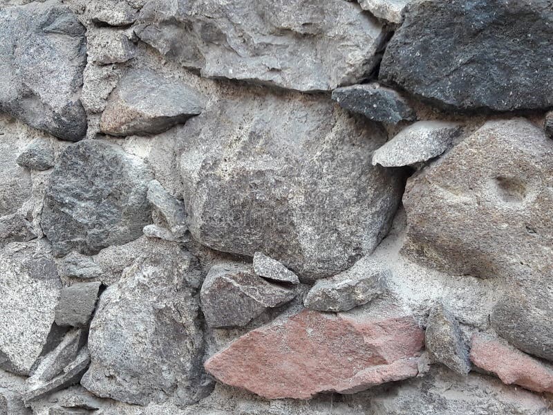 原始烘干与老灰色，桃红色和黑色的墨西哥岩石建筑学的堆样式石墙土气背景纹理
