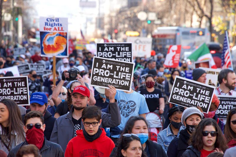 San Francisco, CA - Jan 23, 2021: Unidentified participants at the 17th annual Walk for Life marching down Market street holding pro life signs and banners. People wearing masks, some people not. San Francisco, CA - Jan 23, 2021: Unidentified participants at the 17th annual Walk for Life marching down Market street holding pro life signs and banners. People wearing masks, some people not