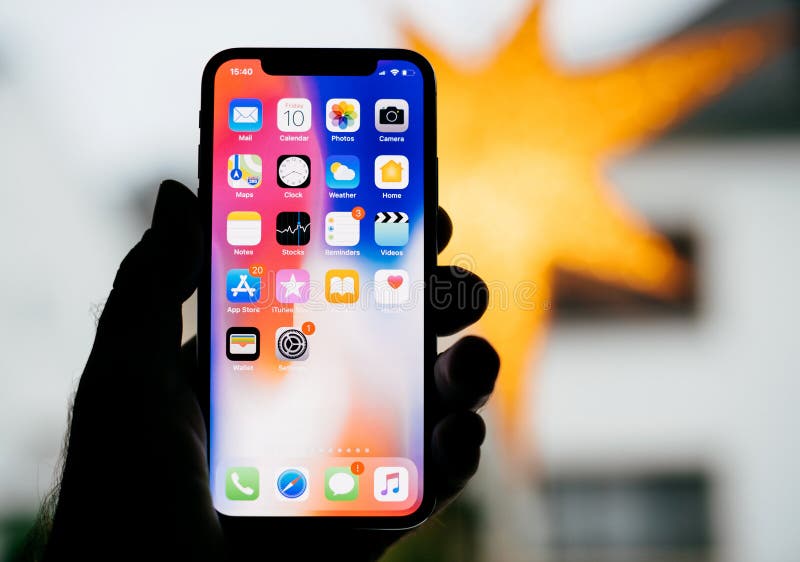 PARIS, FRANCE - NOV 10, 2017: Man holding the new Apple iPhone X 10 Display with yellow star bokeh background featuring all home apps on the Retina screen. PARIS, FRANCE - NOV 10, 2017: Man holding the new Apple iPhone X 10 Display with yellow star bokeh background featuring all home apps on the Retina screen