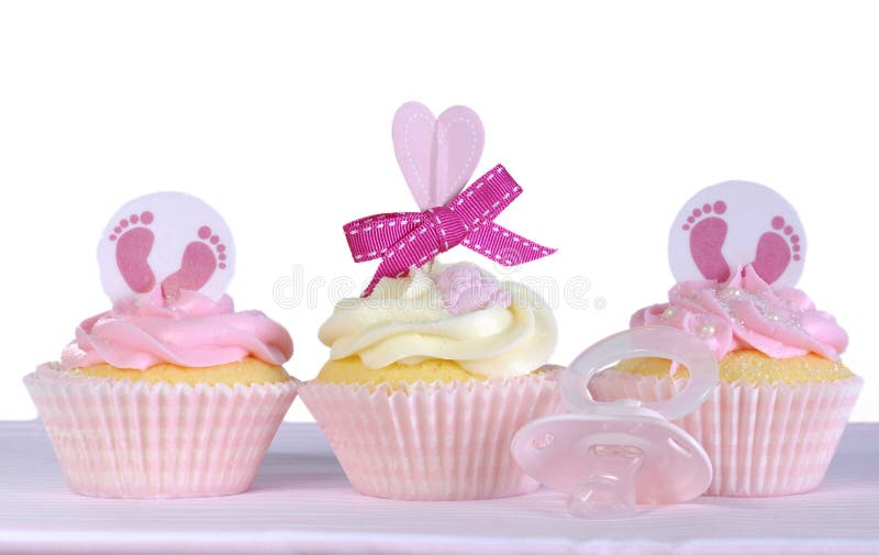 Three pink theme baby girl cupcakes with dummy pacifier against a white background for baby shower or new born nursery greeting card concept. Three pink theme baby girl cupcakes with dummy pacifier against a white background for baby shower or new born nursery greeting card concept.