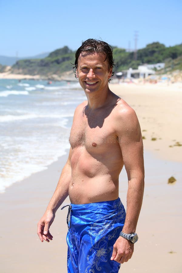 Handsome, fit middle aged man smiling on sandy beach in summer during vacation or holiday. Handsome, fit middle aged man smiling on sandy beach in summer during vacation or holiday