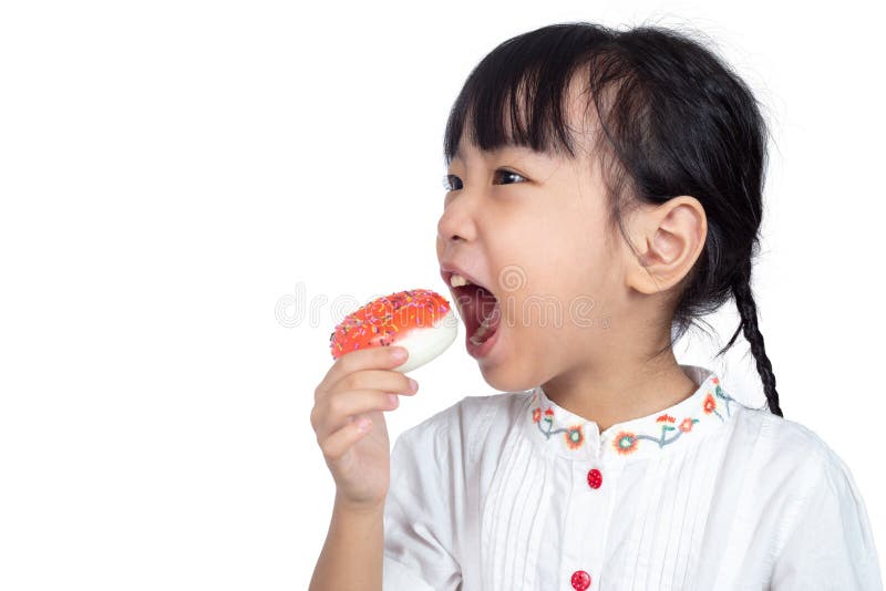 吃油炸圈饼的亚裔矮小的中国女孩 免版税库存照片