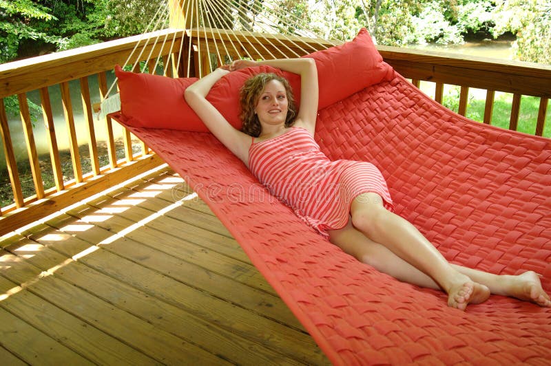 A pretty girl lounging in a hammock on a porch. A pretty girl lounging in a hammock on a porch