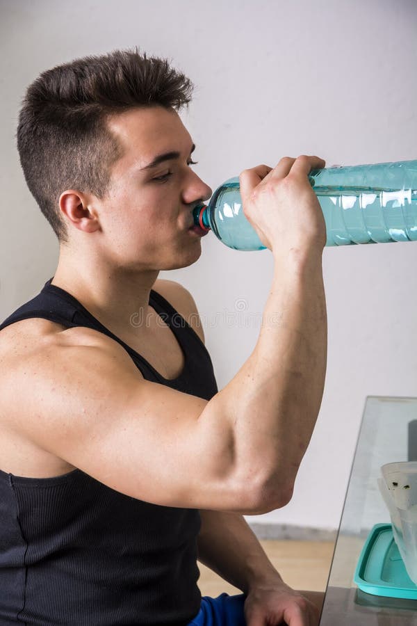 Hungry muscular young man gulping down food glancing across at the camera without pausing as he takes another mouthful. Hungry muscular young man gulping down food glancing across at the camera without pausing as he takes another mouthful