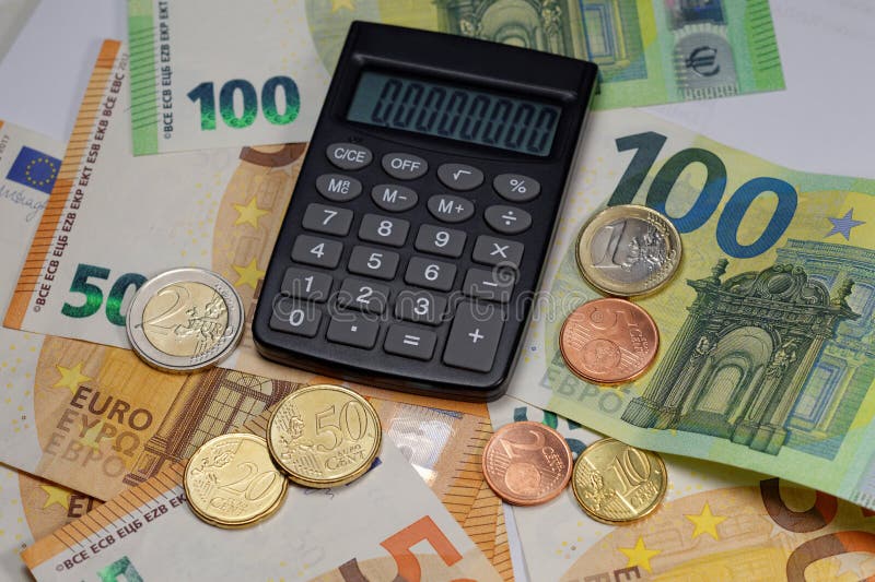 Euro 50 and 100 banknotes and coins with fully visible calculator, perspective view with normal in-focus range. Euro 50 and 100 banknotes and coins with fully visible calculator, perspective view with normal in-focus range