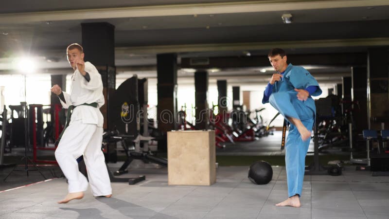 和服练习中的两名武术男子踢脚打拳. 穿着和服训练的男性拳手. 踢拳击运动员