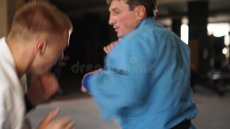 和服练习中的两名武术男子踢脚打拳. 穿着和服训练的男性拳手. 踢拳击运动员