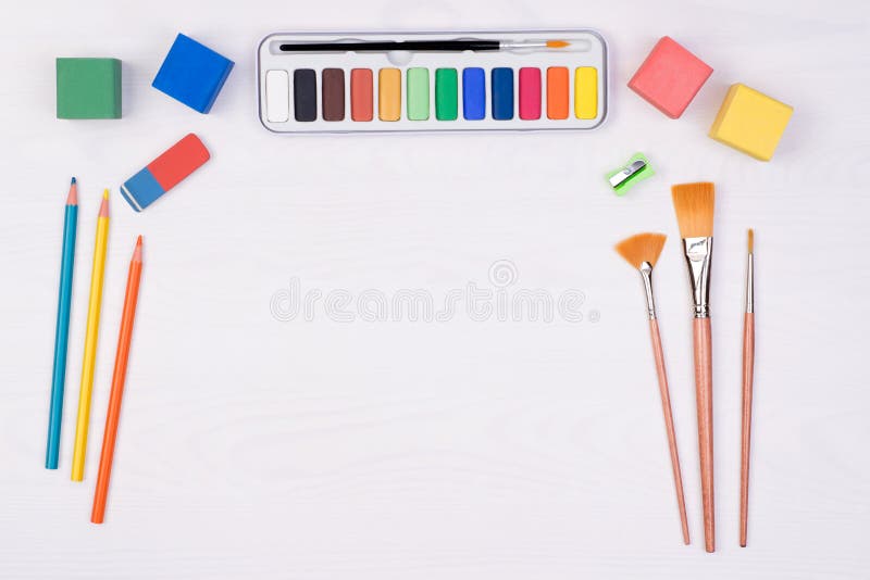 Kid`s desk with colorful pencils, brushes and watercolors, top view with copy space. Kid`s desk with colorful pencils, brushes and watercolors, top view with copy space