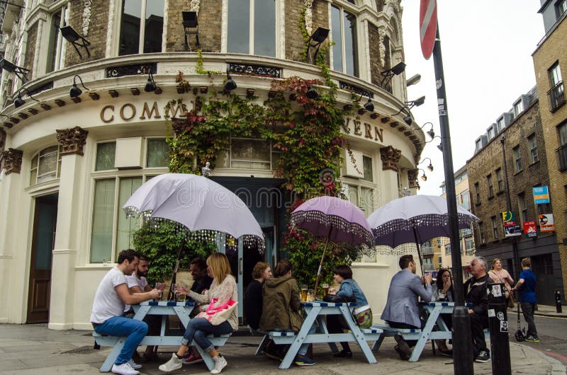 LONDON, UNITED KINGDOM - AUGUST 30, 2014: Drinkers enjoying the open air tables outside the fashionable Commercial Tavern in the hip district of Shoreditch in London's East End. LONDON, UNITED KINGDOM - AUGUST 30, 2014: Drinkers enjoying the open air tables outside the fashionable Commercial Tavern in the hip district of Shoreditch in London's East End.