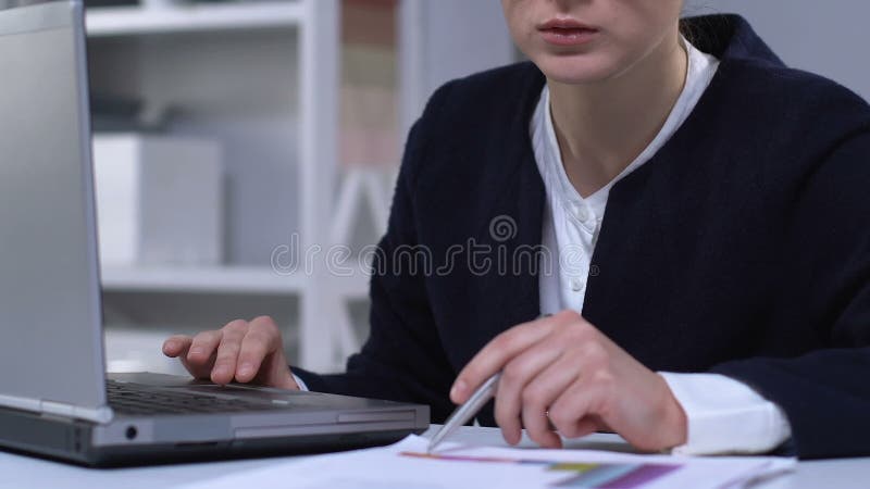 商务妇女比较纸质和笔记本电脑上的财务图表，准备报告