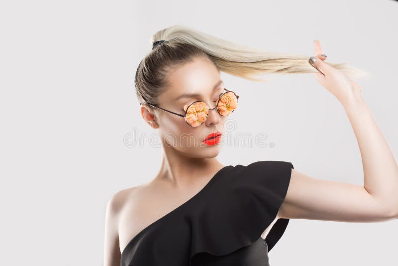 喜欢我的风格和马尾辫 戴着珊瑚花歌眼镜的女女孩摸着,她的金发渐变 免版税库存图片 喜欢我的风格和马尾辫 戴着珊瑚花歌眼镜的女女孩摸着,她的金发渐变 免版税库存图片