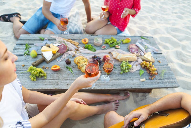 喝在夏天海滩野餐的年轻朋友玫瑰酒红色 库存图片 喝在夏天海滩野餐的年轻朋友玫瑰酒红色 库存图片
