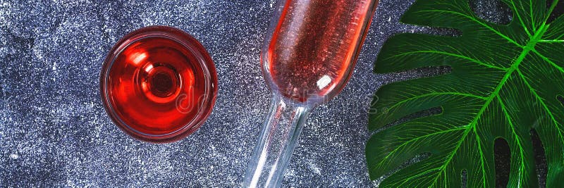 喝酒在葡萄酒杯、瓶和一片热带叶子 顶视图 在灰色背景的酒饮料 复制空间 图库摄影 喝酒在葡萄酒杯、瓶和一片热带叶子 顶视图 在灰色背景的酒饮料 复制空间 图库摄影
