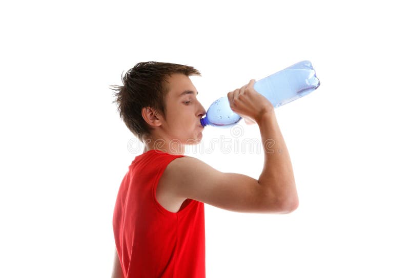 An active young boy teenager drinking bottled water after sport or exercise. White background. An active young boy teenager drinking bottled water after sport or exercise. White background.