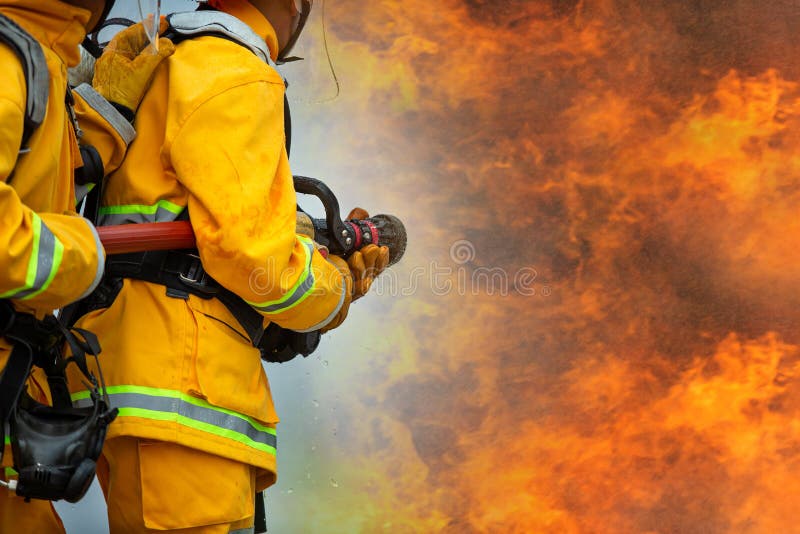 Firefighters spraying high pressure water to fire with copy space, Big bonfire in training, Firefighter wearing a fire suit for safety under the danger case. Firefighters spraying high pressure water to fire with copy space, Big bonfire in training, Firefighter wearing a fire suit for safety under the danger case.