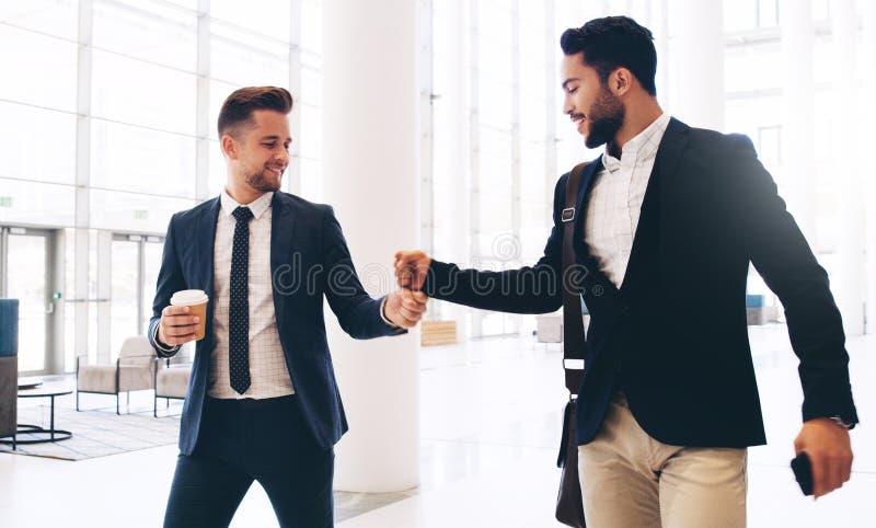 Hey buddy. Cropped shot of two handsome young businessmen greeting each other while in the office during the day. Hey buddy. Cropped shot of two handsome young businessmen greeting each other while in the office during the day