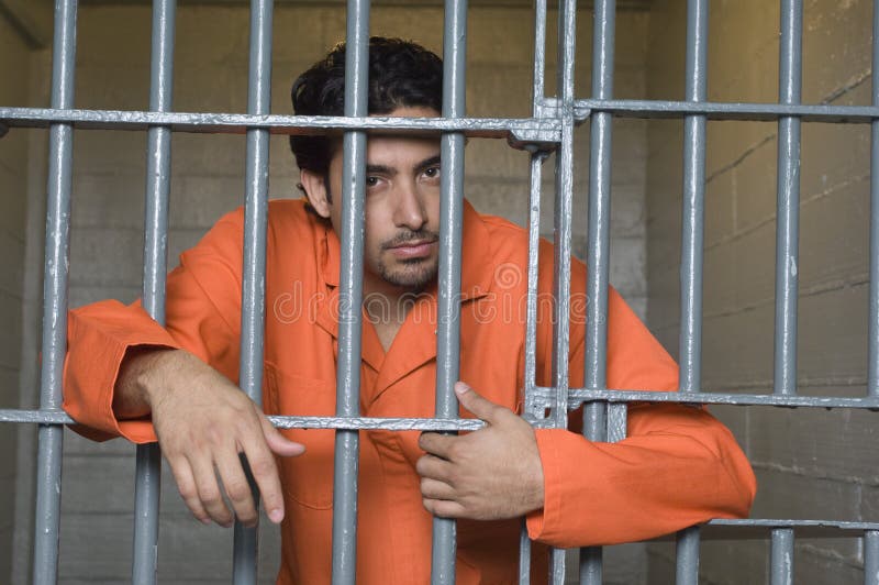 Portrait of prisoner standing behind prison bars. Portrait of prisoner standing behind prison bars