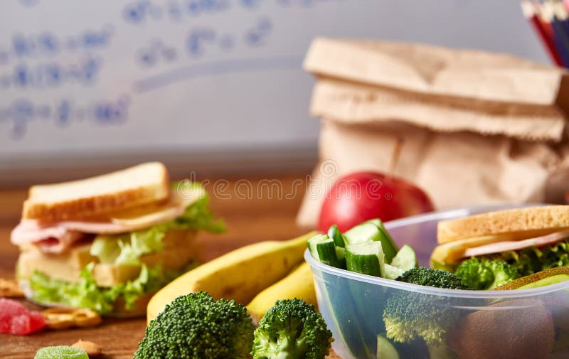 回到学校概念,学校用品,饼干,包装了午餐和饭盒在白色黑板,选择聚焦 免版税库存照片