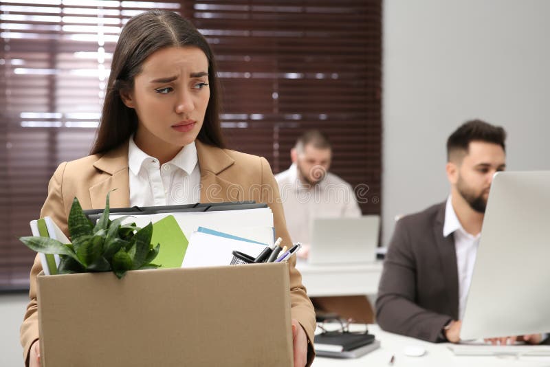 Upset dismissed woman carrying box with personal stuff. Upset dismissed woman carrying box with personal stuff