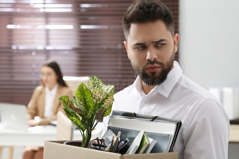 Upset dismissed men carrying box with personal stuff. Upset dismissed men carrying box with personal stuff