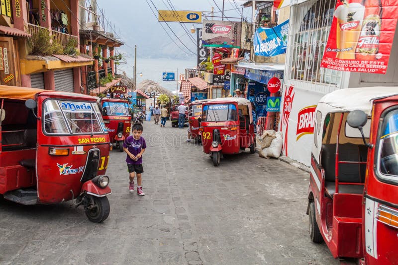 圣地亚哥ATITLAN,危地马拉- 2016年3月24日:tuk tuks行在一条街道上的在圣地亚哥Atitlan villag 免版税库存图片 圣地亚哥ATITLAN,危地马拉- 2016年3月24日:tuk tuks行在一条街道上的在圣地亚哥Atitlan villag 免版税库存图片