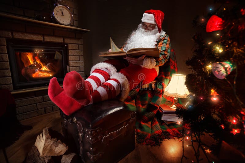 Santa Claus sitting at his room at home near Christmas tree and resting by his fireplace. Santa Claus sitting at his room at home near Christmas tree and resting by his fireplace