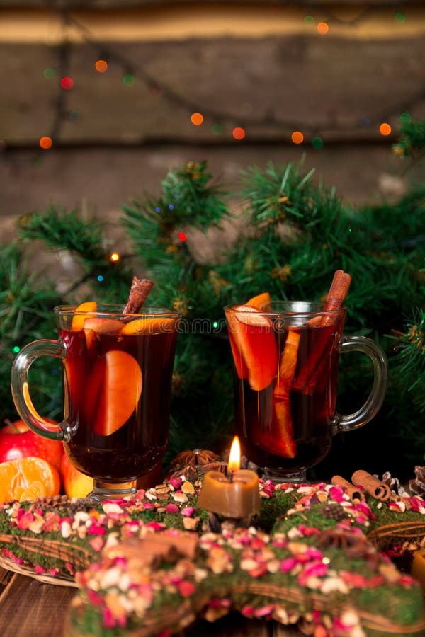 Christmas mulled wine with fruits and spices on wooden table. Xmas decorations in background. Two glasses. Winter warming drink with recipe ingredients around. Christmas mulled wine with fruits and spices on wooden table. Xmas decorations in background. Two glasses. Winter warming drink with recipe ingredients around.