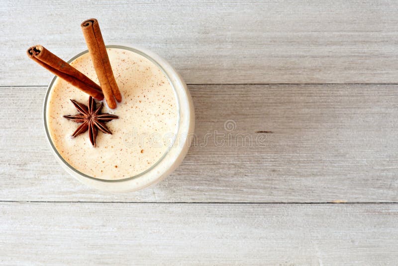 Christmas spiced eggnog in a glass. Top view on a rustic gray wood background. Christmas spiced eggnog in a glass. Top view on a rustic gray wood background.