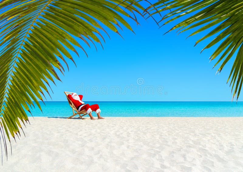 Christmas Santa Claus relaxing on sunlounger at ocean sandy tropical beach under palm leaves. Happy New Year travel destinations to hot countries concept. Christmas Santa Claus relaxing on sunlounger at ocean sandy tropical beach under palm leaves. Happy New Year travel destinations to hot countries concept