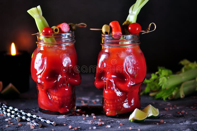 Bloody Mary cocktail in glasses-skull with celery sticks, pink salt, lime and canapes from canned vegetables. food. Bloody Mary cocktail in glasses-skull with celery sticks, pink salt, lime and canapes from canned vegetables. food