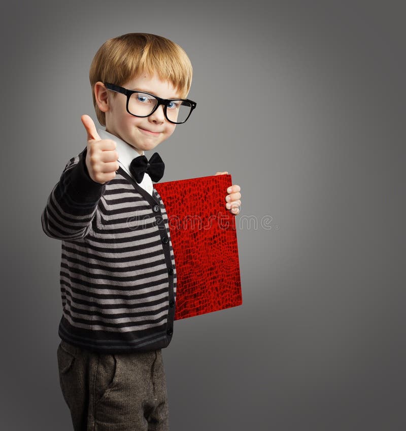 Kid in Glasses, Child Advertiser with Certificate Book, School Boy Showing Thumb Up, Certification Education, gray background. Kid in Glasses, Child Advertiser with Certificate Book, School Boy Showing Thumb Up, Certification Education, gray background