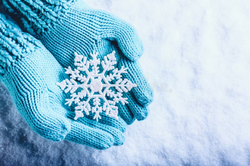 在轻的小野鸭的女性手编织了有闪耀的美妙的雪花的手套在白色雪背景 冬天圣诞节概念