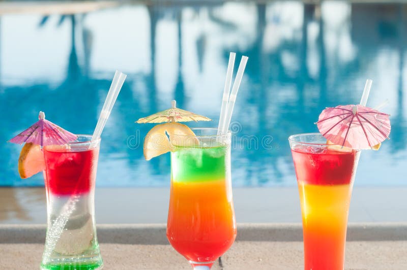 在水背景的色的鸡尾酒 在水池附近的五颜六色的鸡尾酒 海滩党 夏天饮料 库存图片