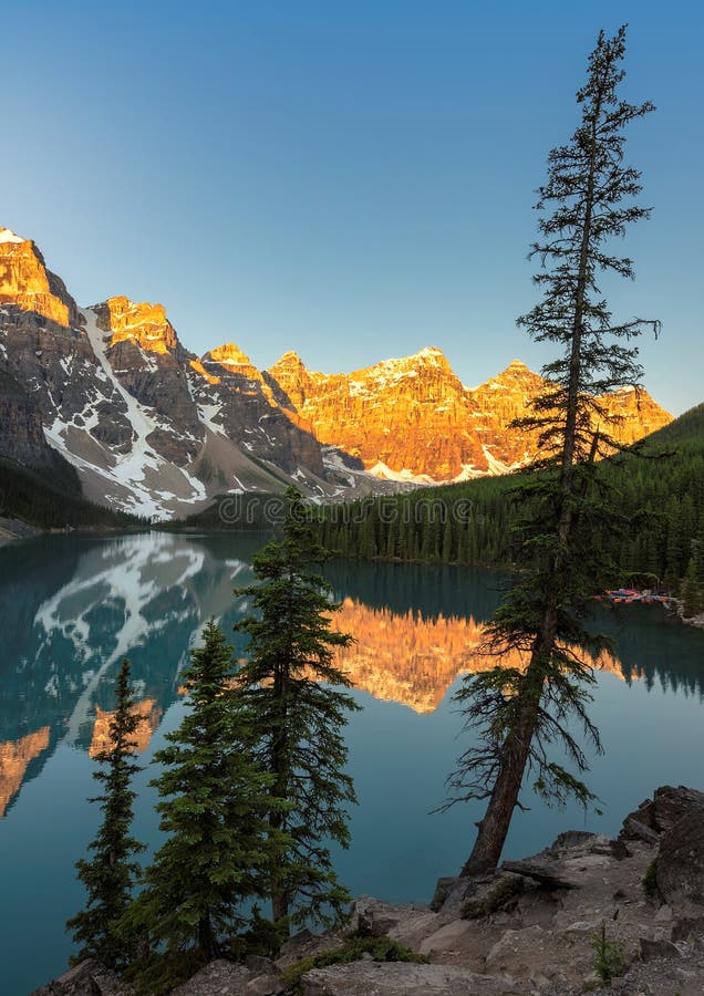 Beautiful sunrise under turquoise waters of the Moraine lake with snow-covered peaks above it in Canadian Rockies, Banff National Park of Canada. Beautiful sunrise under turquoise waters of the Moraine lake with snow-covered peaks above it in Canadian Rockies, Banff National Park of Canada.