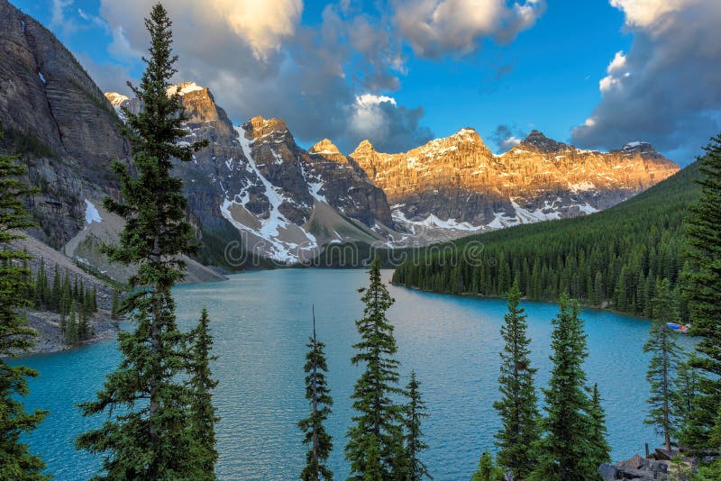 Beautiful sunrise under turquoise waters of the Moraine lake with snow-covered peaks above it in Banff National Park, Rocky Mountains of Canada. Beautiful sunrise under turquoise waters of the Moraine lake with snow-covered peaks above it in Banff National Park, Rocky Mountains of Canada.