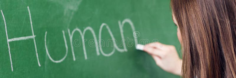 在生物课的年轻女老师教学 写人体的老师在黑板使用白垩 免版税库存照片 在生物课的年轻女老师教学 写人体的老师在黑板使用白垩 免版税库存照片