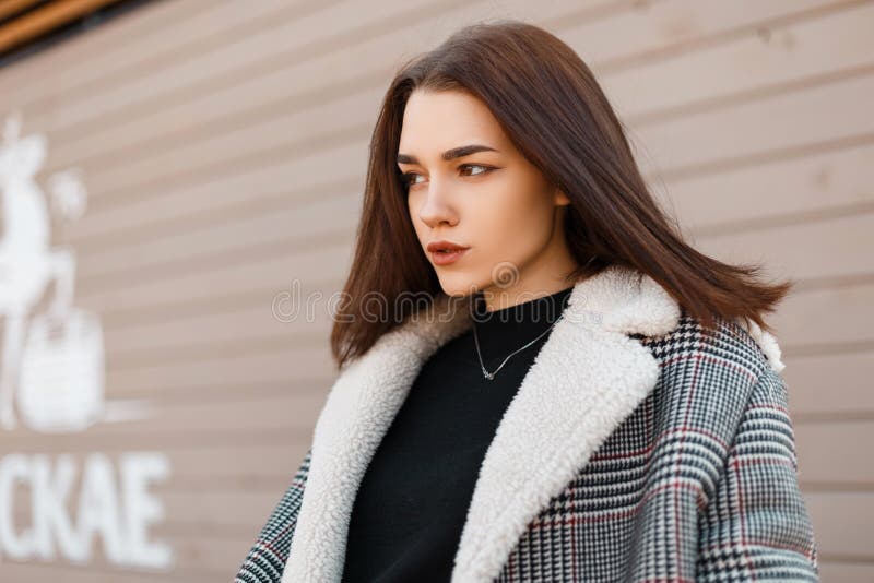 在一件典雅的春天灰色格子花呢披肩外套的俏丽的美好的年轻女人模型在一件黑时髦T恤杉立场 免版税库存图片 在一件典雅的春天灰色格子花呢披肩外套的俏丽的美好的年轻女人模型在一件黑时髦T恤杉立场 免版税库存图片